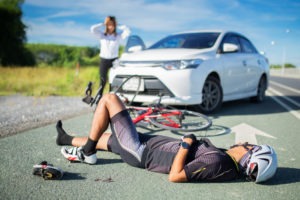 A bicyclist lies on the ground after an accident with a car
