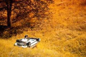 white rolled-over car in fall foliage