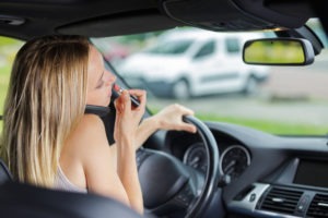 woman on her phone and doing her makeup while driving
