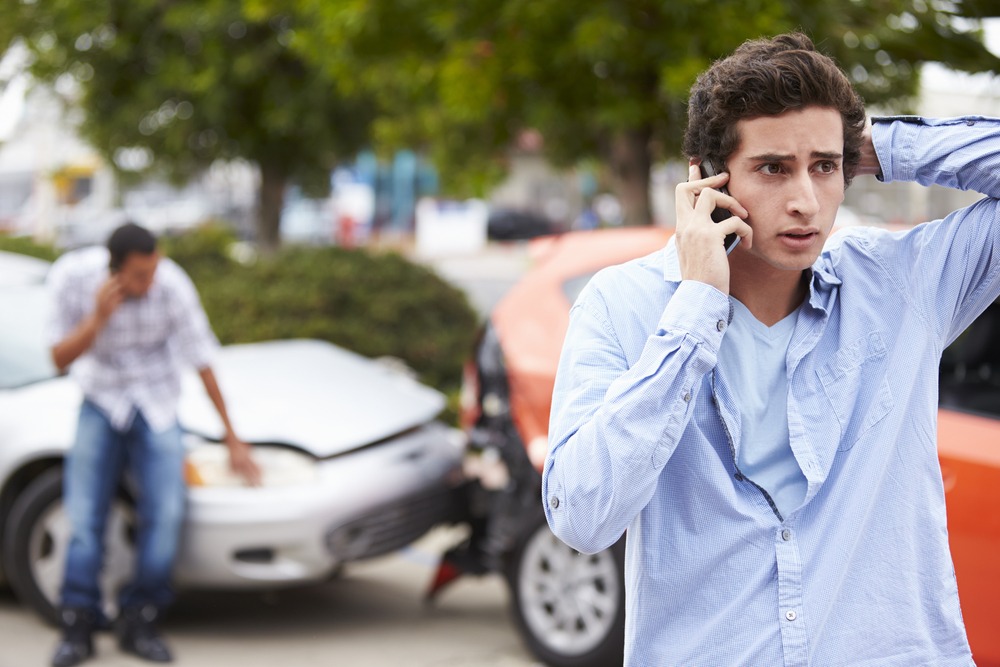 Two male drivers frantically on the phone after a car accident